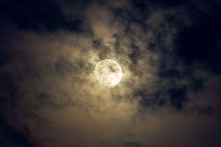 Full moon in the dark cloudy sky at night time. Nature background
