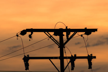 Silhouette of high voltage post with orange sky background, stock photo
