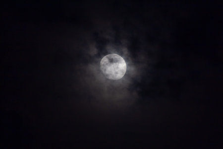 Full moon in the night sky, with white clouds and stars.