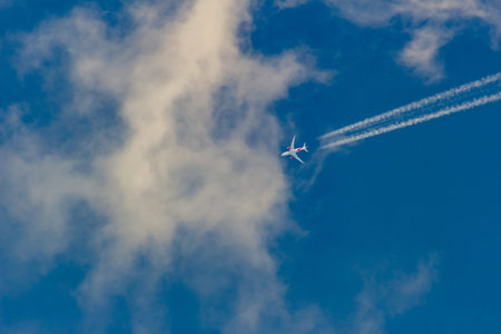 Airplane in the blue sky with white clouds on a sunny day