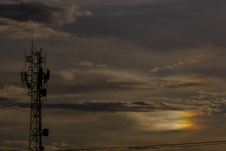 Silhouette of telecommunication tower with beautiful cloudy sky background.