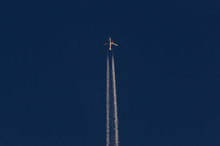 Airplane in the blue sky with white trace of the plane.