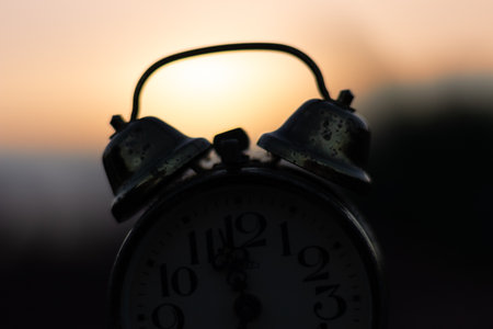 Alarm clock on the background of the setting sun in the eveningの写真素材