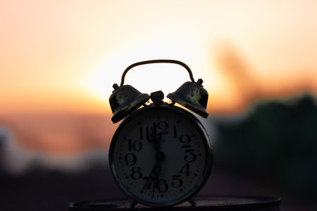 Retro Alarm Clock in the Garden at Sunset or Sunrise timeの写真素材