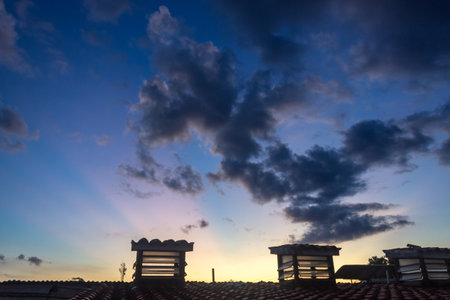 Sunset at the roof of the house with a lot of cloudsの写真素材