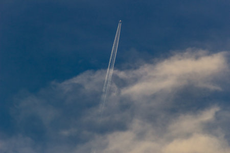Airplane in the blue sky with white clouds and contrail.の写真素材