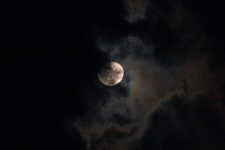 The moon in the night sky in full moonlight with clouds.