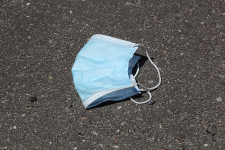 Used medical face mask on the floor in the street