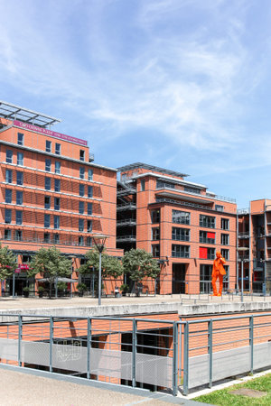 Lyon, France - May 28, 2015: The Cite internationale near parc de la tete d'or in Lyon with the orange statue of businessman in the square of amphitheaterのeditorial素材