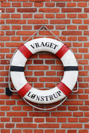 Old lifebuoy hanging on a brick wall in Lonstrup, Denmarkの写真素材