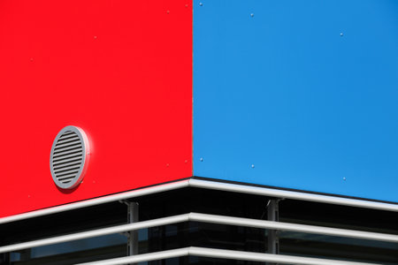 Red and blue facade of a modern office building with ventilation grilleの写真素材