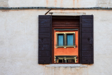 Mirroring in a historical window in Venice, Italy.の写真素材