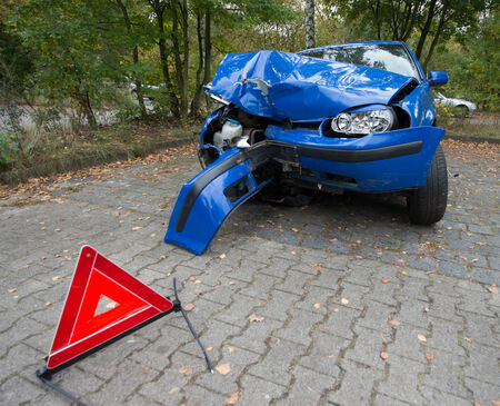 Damaged blue car with red warning triangleのeditorial素材