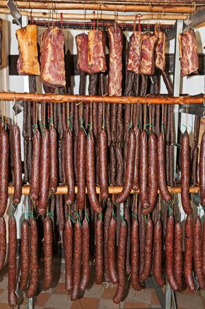 Sausages and hams hanging on wooden shelfの写真素材