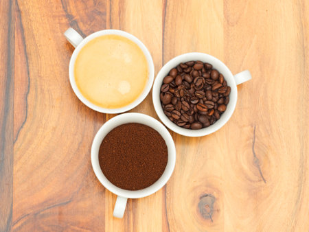 Three cups with coffee, coffee beans and ground coffee on wooden tableの写真素材