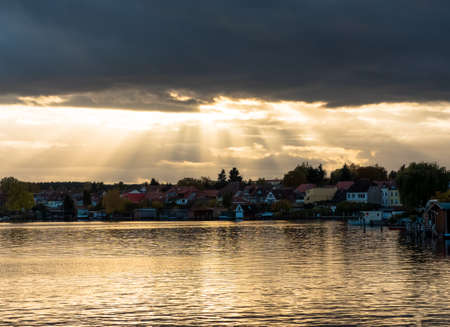 Stormy sky with sun rays on the lakeの写真素材