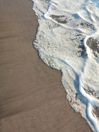 Beach sand sea water summer background. Sand beach texture and white foam wave
