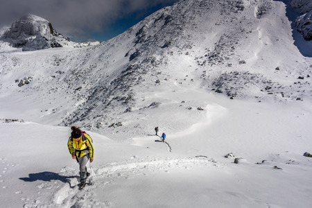 Women climbing the summit at winter and she is being followed by two climbers at the Rila mountain in Bulgaria, Maliovica.のeditorial素材
