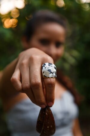 atractive latin woman showing handmade coconut earrings in natureの写真素材
