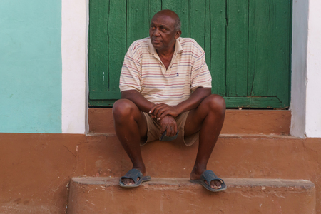 Trinidad, Cuba, January 3, 2017: man on street sitted in front a doorのeditorial素材