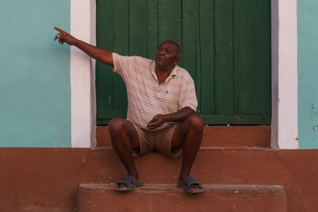 Trinidad, Cuba, January 3, 2017: man on street sitted in front a doorのeditorial素材