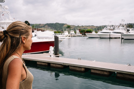 Blonde woman in a harbour looking at moored yachtsの写真素材