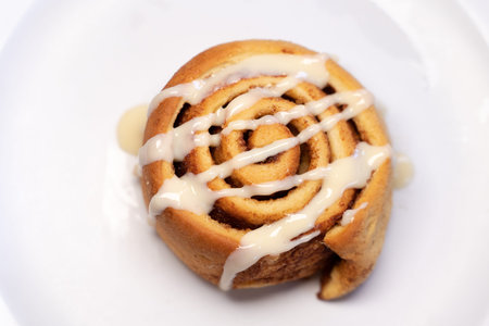 Spiral-shaped pastry decorated with white cream on top in a white backgroundの写真素材