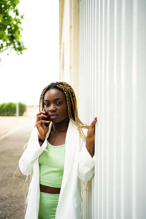 Vertical portrait of an afro woman with braids talking to the mobile outdoorsの写真素材