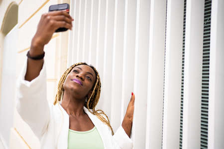 African woman taking a selfie with a mobile with a proud expression outdoorsの写真素材