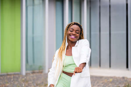 Portrait of a smiling african woman with braids dancing energically outdoorsの写真素材