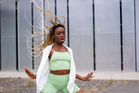 African young woman with braids dancing with energy in an urban landscapeの写真素材