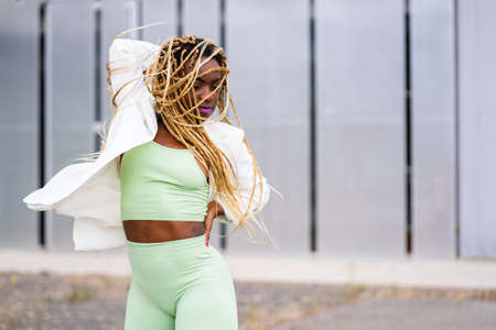 Black woman with braids dancing with energetic movements in a urban landscapeの写真素材