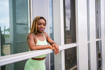 African woman leaning on the railing of a modern building in sports clothesの写真素材