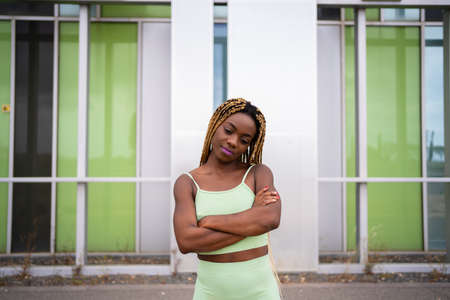 African sportive woman posing with arms crossed in front of a modern facadeの写真素材