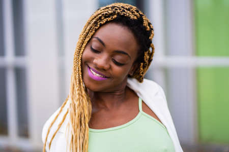 Beauty young african woman with braided hair smiling in a urban landscapeの写真素材