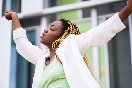 Beauty african woman dancing with the arms raised with passion outdoorsの写真素材