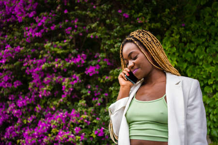 Smiling african woman in sports clothes talking on the mobile outdoorsの写真素材