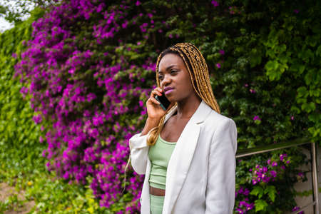 African woman in sports clothes talking seriously on the mobile outdoorsの写真素材