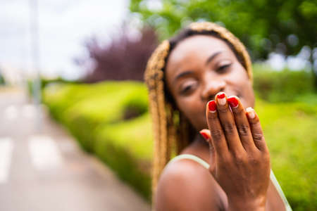 Young african woman gesturing a kiss to the camera outdoorsの写真素材