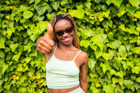 Black woman with sunglasses gesturing to be okay facing the camera outdoorsの写真素材