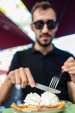 Focus on a man cutting a crepe with cream on a restaurantの写真素材