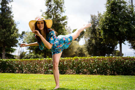 Woman in dress and hat raising the leg while perform a dance outoorsの写真素材
