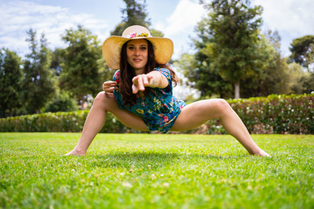 Woman in summer clothes pointing ahead while dancing freestyle in a gardenの写真素材