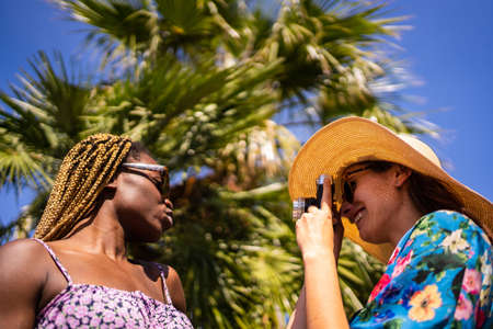 Woman in straw hat taking pictures with a camera of an african womanの写真素材