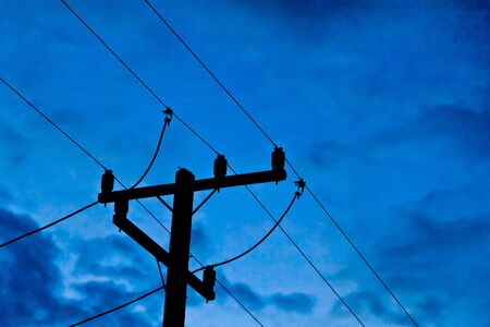 The silhouette image of an electricity post with blue skyの写真素材