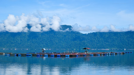 fish cages on the lake with hills blue sky and cloud background.の写真素材