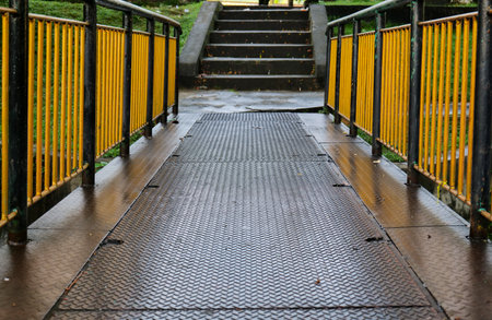 Metal walkway in the park on a rainy day with yellow railingの写真素材