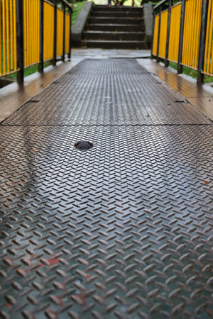 Walkway in the park with a black metal floor and yellow fenceの写真素材