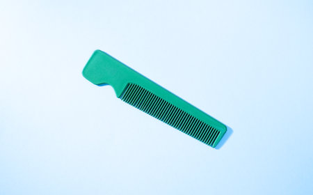 Green plastic comb on blue background. Top view. Flat lay.の写真素材