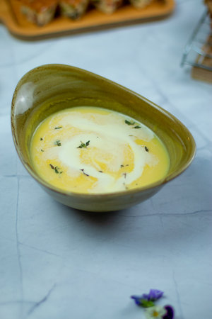 Pumpkin soup with cheese and herbs in a bowl on the table. Good for any festive or family gathering.の写真素材